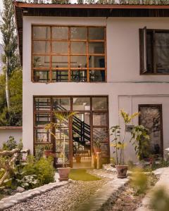 罕萨Offto Resort Hunza的院子里有大窗户和植物的房子