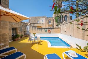 加斯利Gozo Escape的庭院设有游泳池、椅子和桌子。