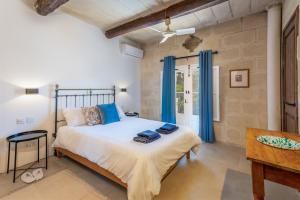 阿尔卜Dar ta' Betta Farmhouse with private pool的一间卧室配有一张带蓝色窗帘的大床