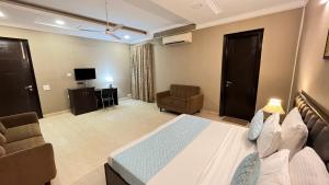 新德里Abode Residency Safdarjung Enclave Near U S Embassy Delhi的一间卧室配有一张床、一张沙发和一台电视