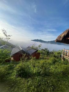 Hoàng Su PhìHomestay Chân Mây Chiêu Lầu Thi的享有带两栋建筑和一座山丘的雾 ⁇ 区的景色