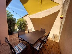 圣萨蒂南艾普特Maison de César的木制甲板上配有带黄伞的桌椅