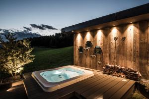 卡斯特尔罗托Alpin Boutique Villa Gabriela - Adults Only的木制甲板上的一个按摩浴缸