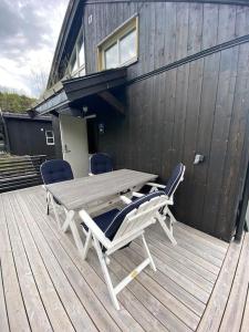 斯特兰达Hytteleilighet på Strandafjellet的一张木桌和椅子,坐在甲板上