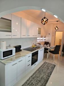 下米拉诺瓦茨Apartman Jovanovic的厨房配有白色橱柜和带微波炉的桌子。