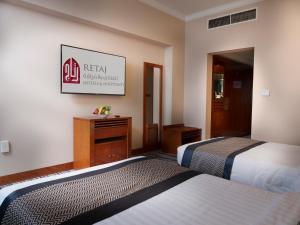 多哈艾尔瑞安瑞塔杰酒店的酒店客房设有两张床,墙上有标志