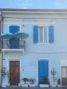 维亚雷焦Villa Valentina Versilia的蓝色的房子,设有蓝色百叶窗和一个带两把遮阳伞的阳台