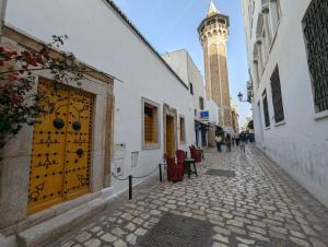 突尼斯Dar Hamouda Guest House - Médina de Tunis的一条狭窄的街道,后面有钟楼