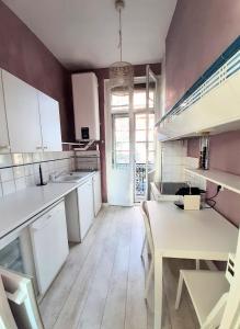 图卢兹Appartement Pont des Catalans的一间大厨房,配有白色的橱柜和一张桌子