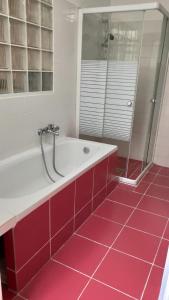维也纳CozyNite Premium Apartment Stadthalle的带浴缸的浴室和红色瓷砖地板。