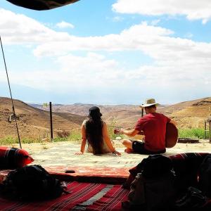 阿拉德Desert's Edge Eco Tent的两个人坐在一张桌子上,眺望着群山