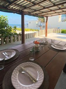 莫雷洛斯港Casa Lucia Beachfront Puerto Morelos的一张木桌,上面有盘子和餐具