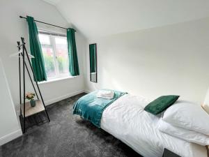 伯明翰Perfect for Contractors & Families! 7 Beds Free Parking的一间卧室设有床铺和一个带绿色窗帘的窗户。
