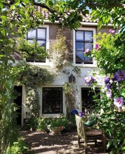 豪达Apple Tree Cottage - discover this charming home at beautiful canal in our idyllic garden的房屋前有椅子和鲜花