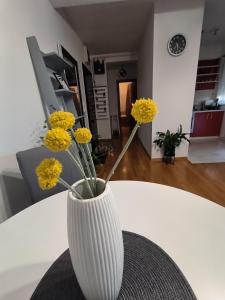 扎普雷希奇Apartman Jurak的白色花瓶,黄花坐在桌子上