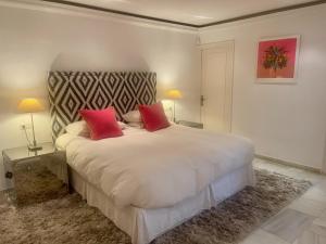 马贝拉Villa in a palm tree plantation的卧室配有一张带两个红色枕头的大型白色床