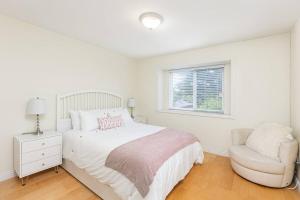 温哥华Home near Downtown Vancouver East@ Joyce Skytrain的白色卧室配有床和椅子