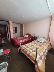 拉塔昆加Como en casa的一间卧室配有两张床、一张桌子和一把椅子