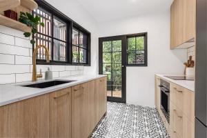 悉尼Ultimo l Renovated 2 Bedroom House With Rooftop Balcony的厨房配有木制橱柜,铺有黑白瓷砖地板。