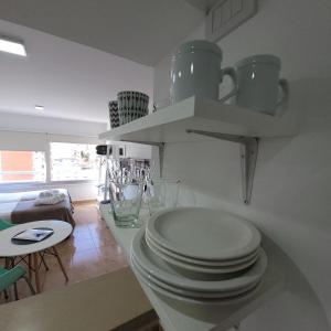 拉普拉塔Calle 10 - Monoambiente的一间白色的厨房,在柜台上堆放一块盘子