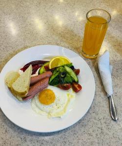 乌兰巴托Sunjin Grand Hotel的包括鸡蛋香肠、蔬菜和一杯果汁的早餐食品