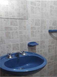乌玛瓦卡Hostal El Farolito的浴室设有蓝色水槽和瓷砖墙