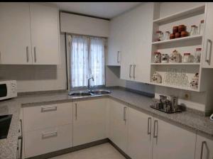布埃乌Mi casa es la tuya的厨房配有白色橱柜、水槽和窗户。