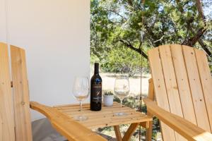 伯尼Twin Falls Luxury Glamping - Cozy Retreat的木桌旁的一瓶葡萄酒和两杯酒