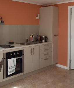 马斯特顿Bunny Cottage的厨房配有白色橱柜和橙色墙壁