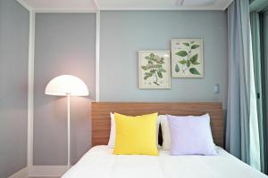 釜山Elmomento Gwangan的一间卧室配有黄色和白色枕头的床