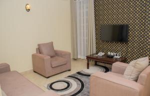 纳库鲁Pearl Suites Apartments的客厅配有两把椅子和墙上的电视