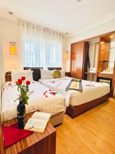 河内Elite Central Hotel Hanoi的一间卧室配有两张床和一张桌子及书籍