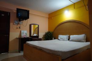 卡纳科纳Dmello Guest House的一间卧室配有一张大床和一台平面电视