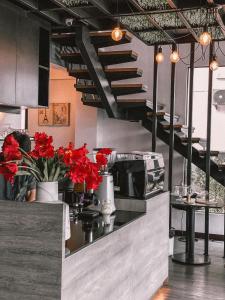 巴吞他尼Campagne Hotel and Residence - SHA Plus的柜台和楼梯上种有红色鲜花的厨房