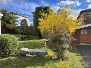 EcublensIndividual house free parking wifi Netflix Disney next to EPFL Lausanne的一座花园,花园内设有石凳和鲜花