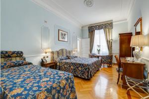 罗马Hotel Cellini的酒店客房设有两张床和一张桌子。