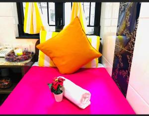 香港阿肖克旅舍的粉红色的桌子,上面有枕头和花瓶