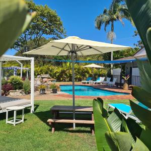 扬巴The Carmel Yamba的一个带遮阳伞、长凳和游泳池的庭院