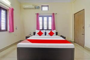 德拉敦Balindira Guest House的一间卧室配有一张带红色枕头的大床