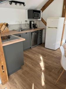 阿宰勒里多Gîte au 1er étage avec jardin的厨房铺有木地板,配有白色冰箱。