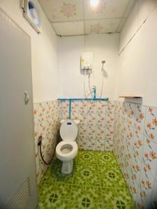 高兰Baan phuwamin的一间带卫生间的浴室,铺有绿色地板。
