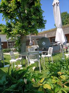 CanapvilleAuberge du Vieux Tour Le Manoir的庭院配有桌椅和遮阳伞。