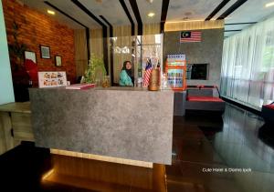 怡保怡保可爱酒店及旅馆的站在餐厅柜台后面的女人