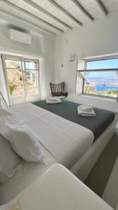 米克诺斯城Alia Luxury Villa Mykonos的白色卧室设有一张大床和两个窗户