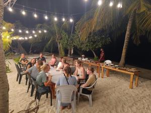 迪弗西The Sunset Villa的一群人晚上坐在海滩的桌子上