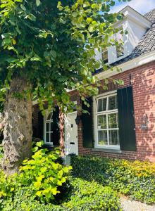HelvoirtBed and Breakfast: 'Bij ons Achter'的砖屋,有白色的门和一棵树