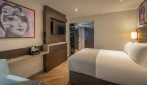 伦敦Maldron Hotel Finsbury Park, London的配有一张床和一把椅子的酒店客房