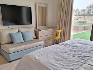 塞拉莱Hawana Salalah Lake View Villa 22的一间卧室配有电视、沙发和椅子