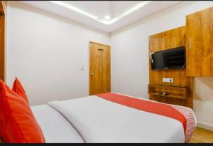 艾哈迈达巴德HOTEL SAFARI INN的卧室配有白色的床和墙上的电视。