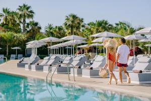 帕福斯Ivi Mare - Designed for Adults by Louis Hotels的两人在度假村的游泳池边散步